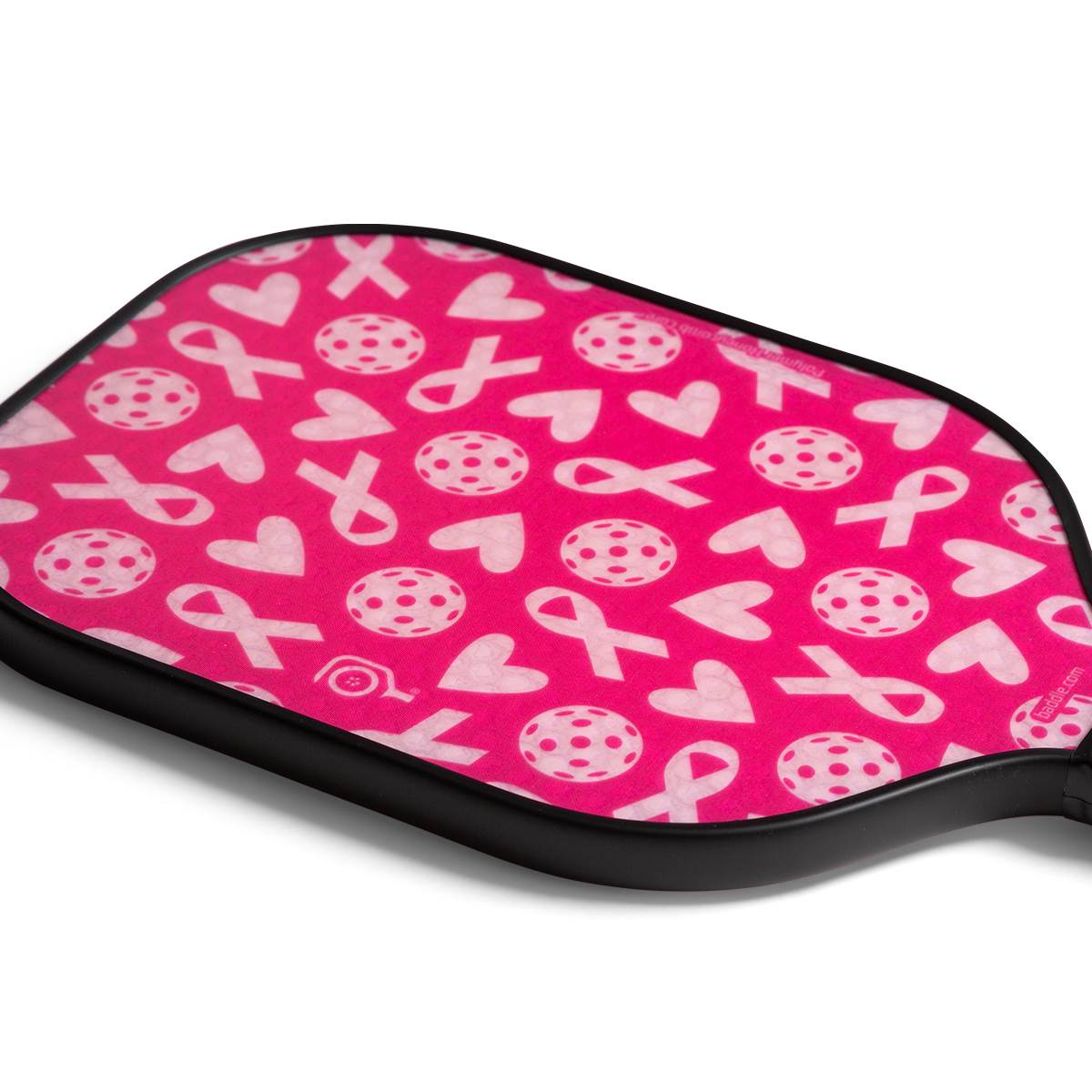 Corner view of a pink pickleball paddle with a pattern of white ribbons, hearts, and pickleballs.