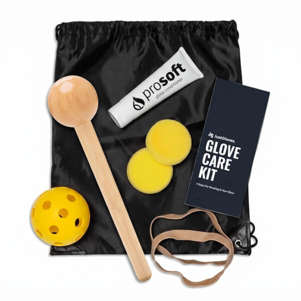 Top-down view of a black drawstring bag containing a wooden ball on a stick, a yellow ball, a tube of "prosoft" glove conditioner, and a "JustGloves. GLOVE CARE KIT" card.