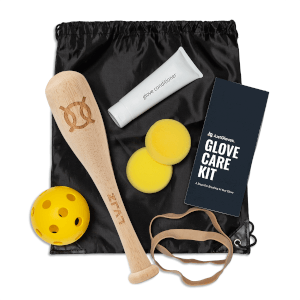 Top-down view of a baseball glove care kit containing a wooden bat, yellow ball, conditioner tube, and instruction booklet.