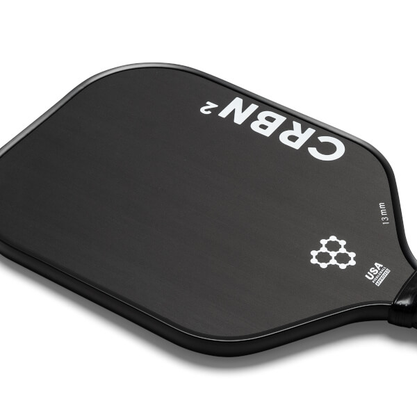 Top-down view of a black pickleball paddle with white CRBN² branding, a honeycomb logo, and 13 mm USA Pickleball Approved text.