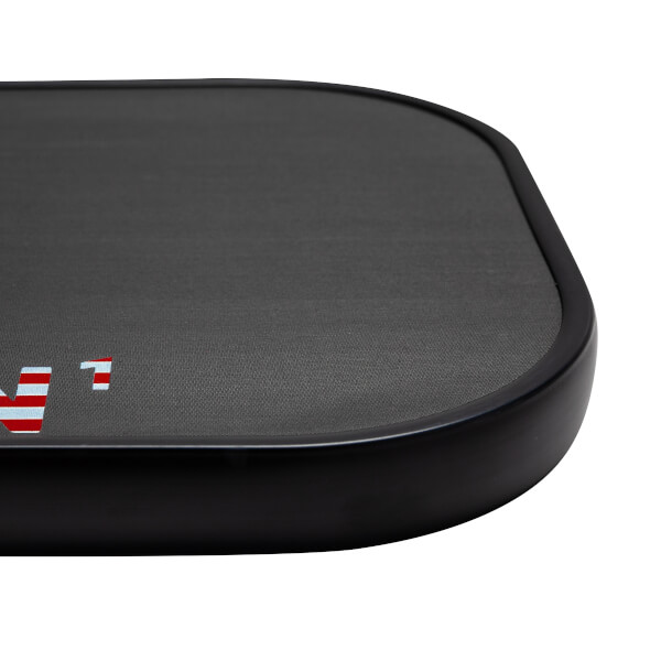 Corner view of a black pickleball paddle with a textured surface and red and white stripes.
