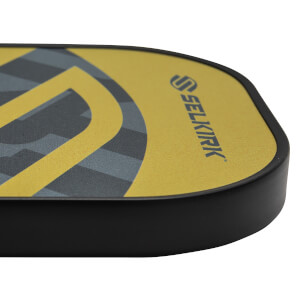 Corner view of a yellow pickleball paddle with a black edge and Selkirk logo.