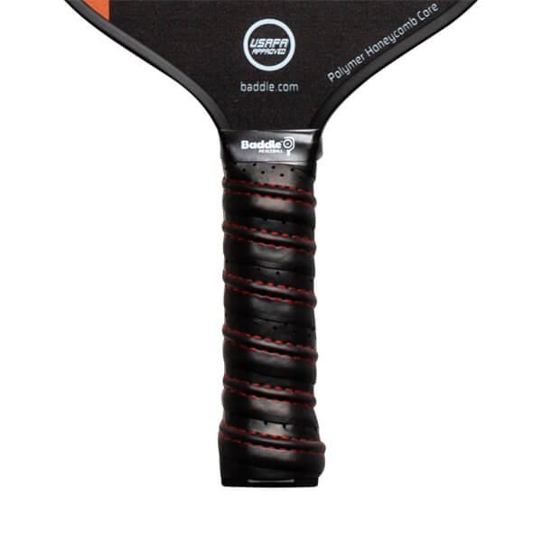 Close-up of a black pickleball paddle grip with red stitching and Baddle branding.