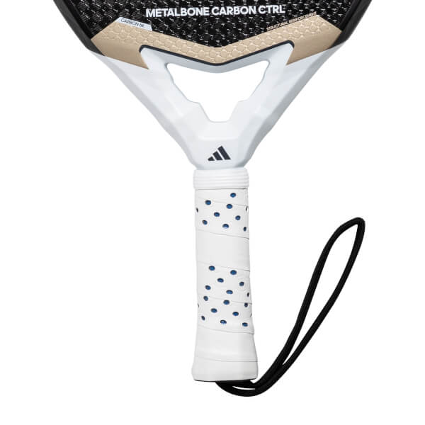 Close-up of a white padel racket grip with blue dots and a black wrist strap, showing METALBONE CARBON CTRL text.