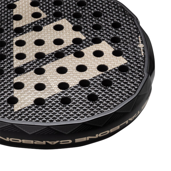 Corner view of a black padel racket with gold diamond pattern and CARBON text.