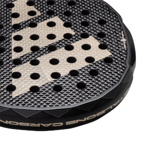 Corner view of a black padel racket with gold diamond pattern and CARBON text.