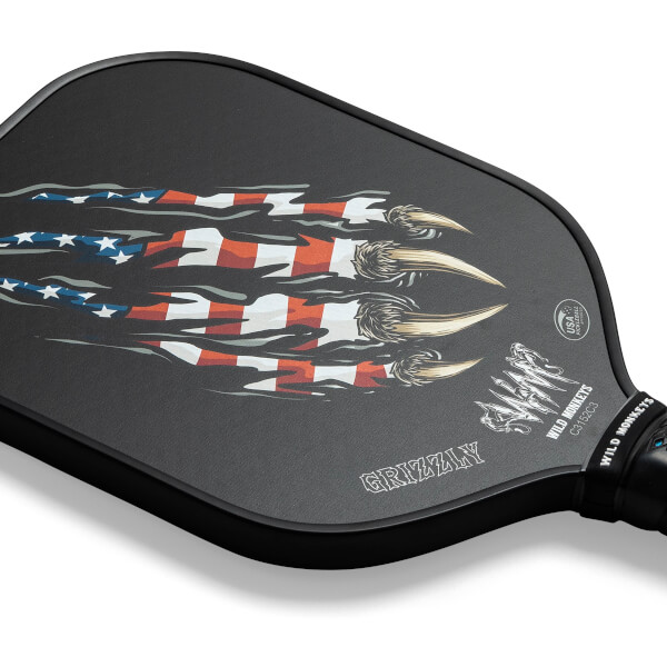 Corner view of a black pickleball paddle with a claw and American flag graphic, and GRIZZLY text.