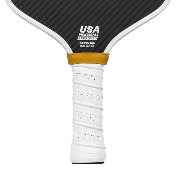 Close-up of a white pickleball paddle grip with perforations and a gold band above the USA Pickleball Approved logo.