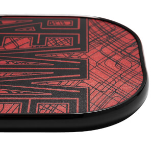 Corner view of a black and red pickleball paddle with geometric line patterns and bold lettering.