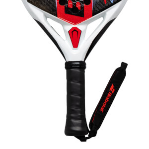 Close-up of a white and red padel racket handle with a black grip and a Babolat wrist strap.