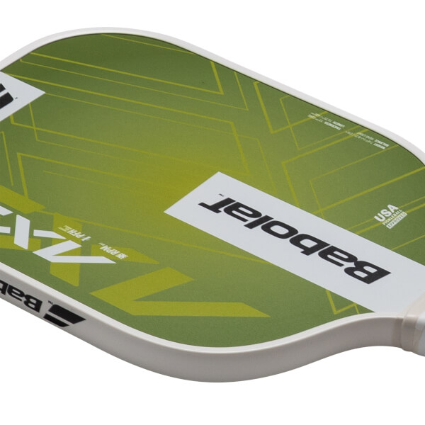 Top-down view of a pickleball paddle with green and yellow geometric design, showing "Babolat" and "USA PICKLEBALL APPROVED".