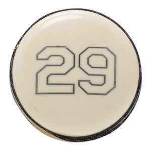 Close-up of a cream baseball bat end cap with a glossy finish and the number 29 outlined in black.