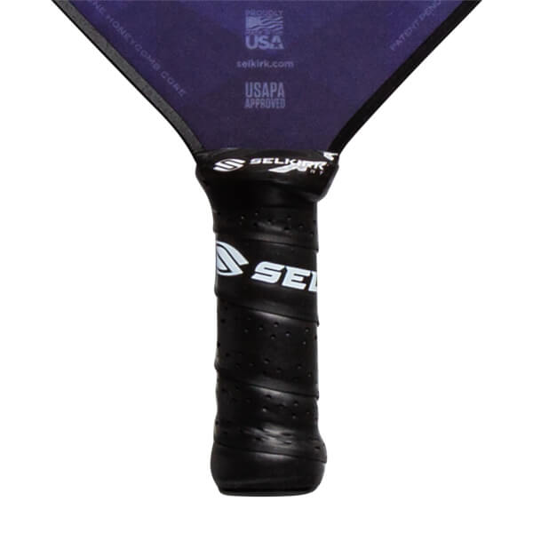 Close-up of a black pickleball paddle grip with white Selkirk branding and USAPA Approved text on the purple paddle head.