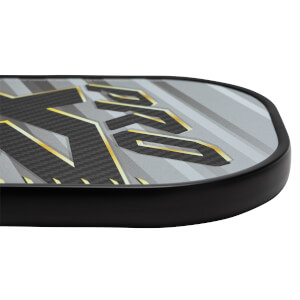Corner view of a gray pickleball paddle with carbon fiber texture and gold PRO lettering.