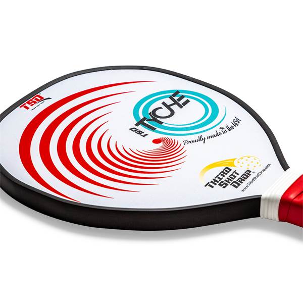 Corner view of a white pickleball paddle with red swirl design, TYCHE logo, and Proudly made in the USA text.
