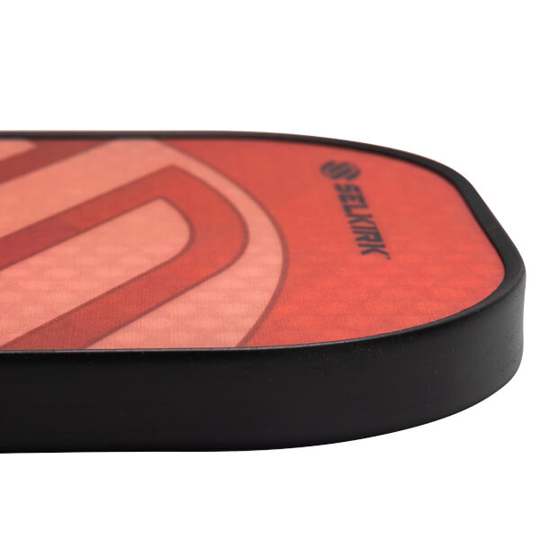 Corner view of a red pickleball paddle with a black edge and Selkirk branding.