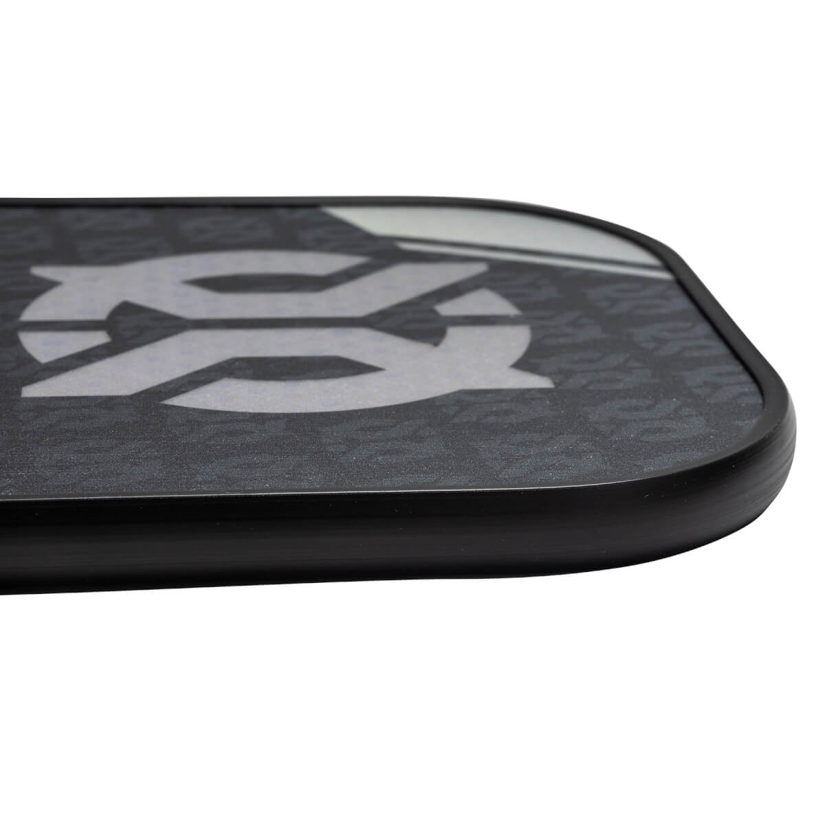 Corner view of a black pickleball paddle with a large white SS logo and repeating pattern.
