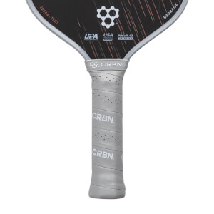 Close-up of a light gray perforated pickleball paddle handle with CRBN branding, connected to a black Barrage paddle face.