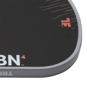 Close-up of a black pickleball paddles bottom right corner with a grey edge guard, white CRBN4 text, and orange TF logo.