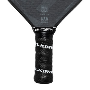 Close-up of a black pickleball paddle grip with embossed Selkirk branding and USA Pickleball Approved text on the paddle head.