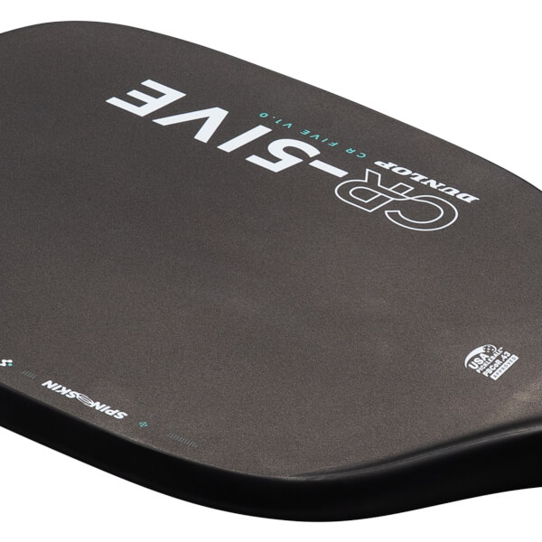 Close-up view of the black paddle face featuring white and teal DUNLOP CR-FIVE V1.0 branding, SPIN SKIN along the edge, and the USA Pickleball logo.