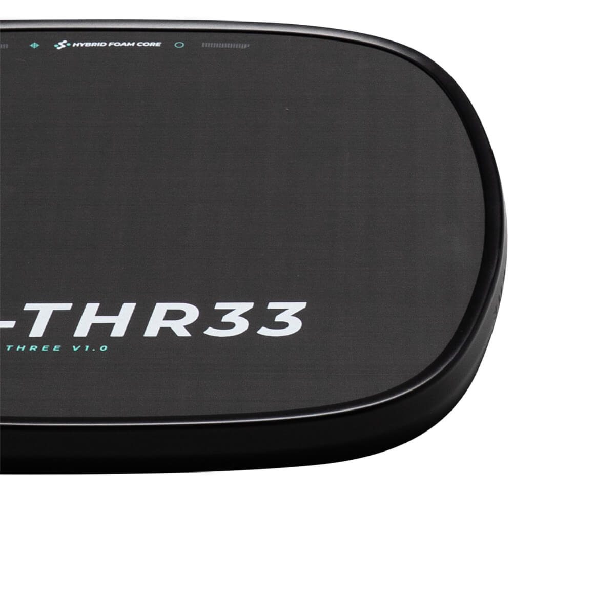 Close-up corner of the black paddle surface showing white "-THR33" text and a teal "HYBRID FOAM CORE" label along the rounded edge.