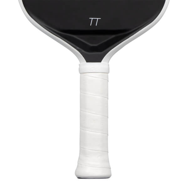 Close-up view of a paddle showing its white wrapped handle and the lower portion of its black face featuring a white TT logo.