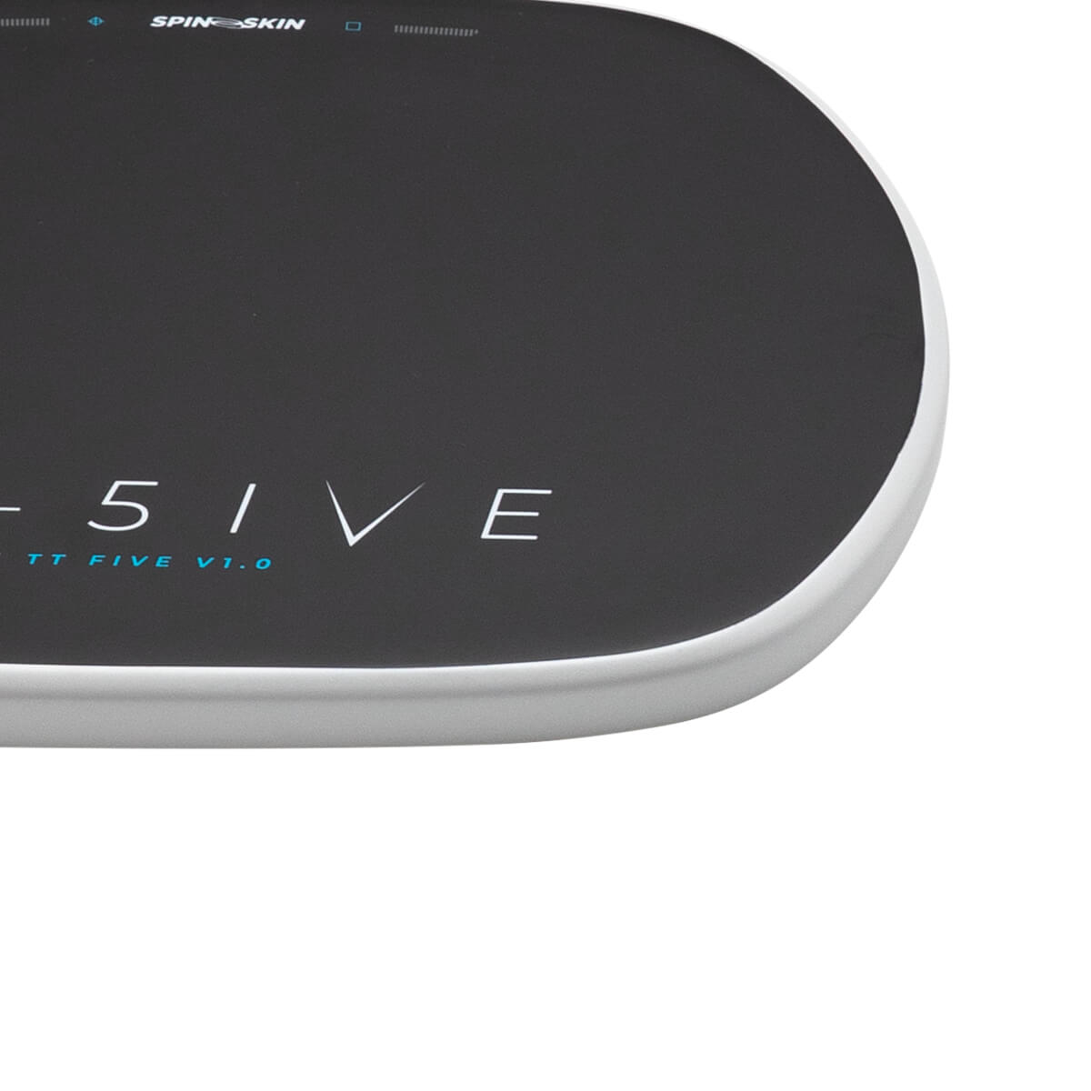 Close-up corner view of a dark textured mat with a white rounded edge, featuring SPINE SKIN, 5IVE, and TT FIVE V1.0 text on the surface.