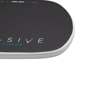 Close-up corner view of a dark textured mat with a white rounded edge, featuring SPINE SKIN, 5IVE, and TT FIVE V1.0 text on the surface.