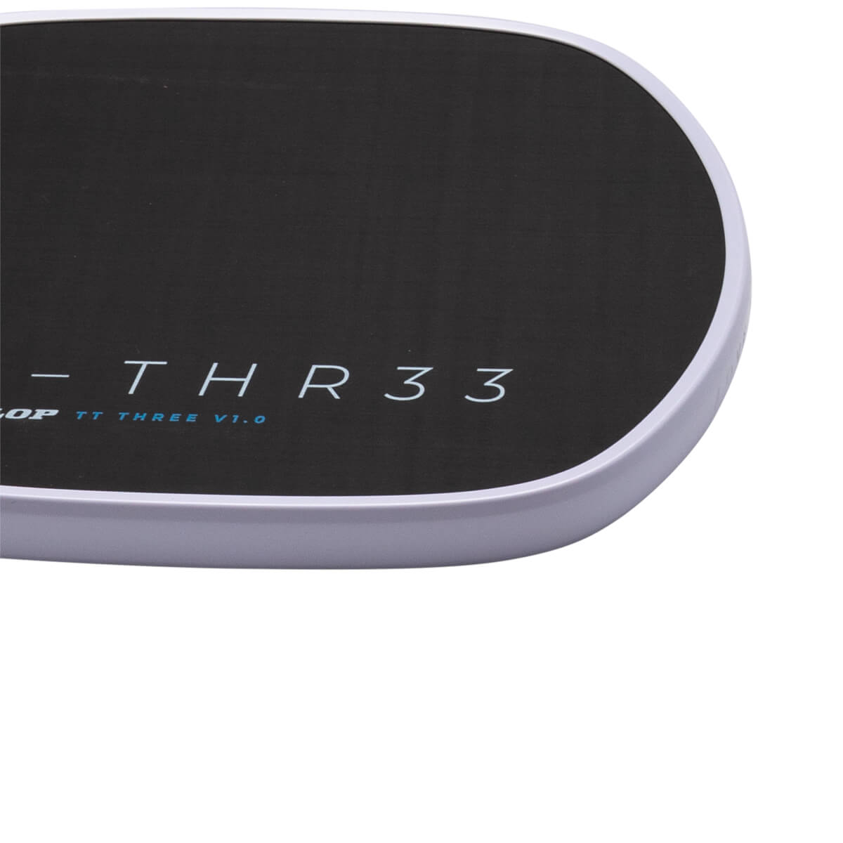 Close-up corner view of a black surface with a light-colored rim, featuring the text "THR33" in white and "TT THREE V1.0" in blue.