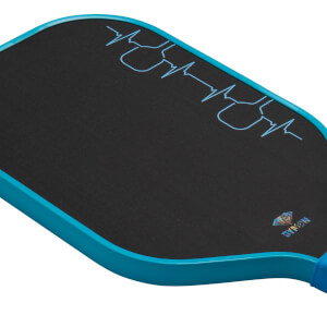 Close-up angled view of the black paddle face and teal edge guard, highlighting a blue heartbeat graphic with paddle shapes and a small DYMON logo.