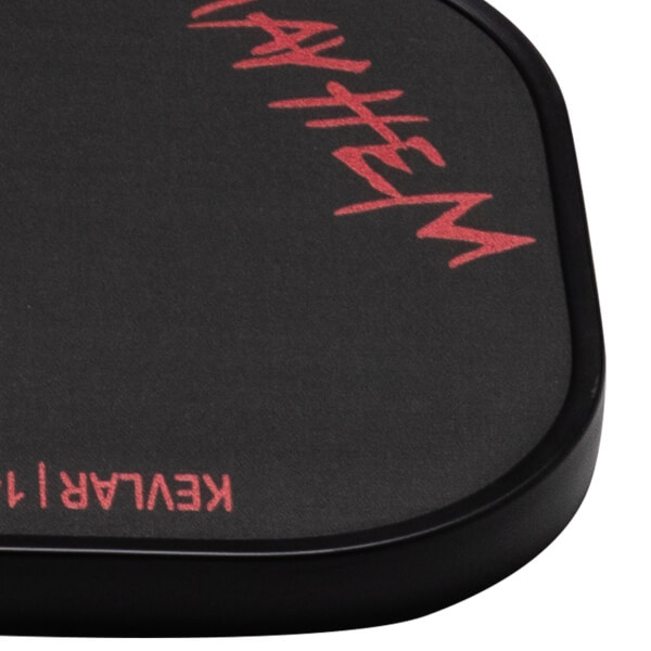 Corner view of the Dymon Mayhem paddle showing red "MAYHEM" text and "KEVLAR 14" on the black carbon fiber surface.