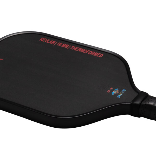 Close-up of a black pickleball paddle showing "KEVLAR | 16 MM | THERMOFORMED" and the "DYMON" logo.