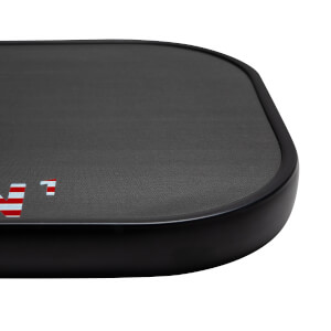 Corner view of a black pickleball paddle with a textured surface and red and white stripes.