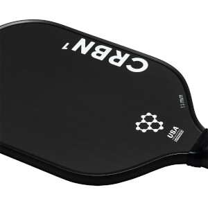 Corner view of a black pickleball paddle with white CRBN¹ branding, a molecular graphic, and USA Pickleball Approved text.