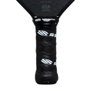Close-up of a black pickleball paddle grip with white Selkirk logos and leaf-like texture.