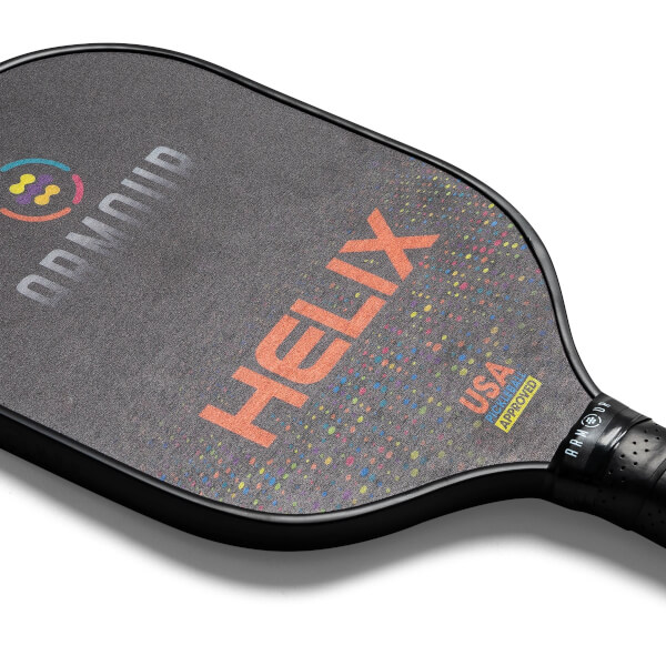 Top-down view of a black pickleball paddle with orange HELIX text, colorful speckles, and USA Pickleball Approved logo.