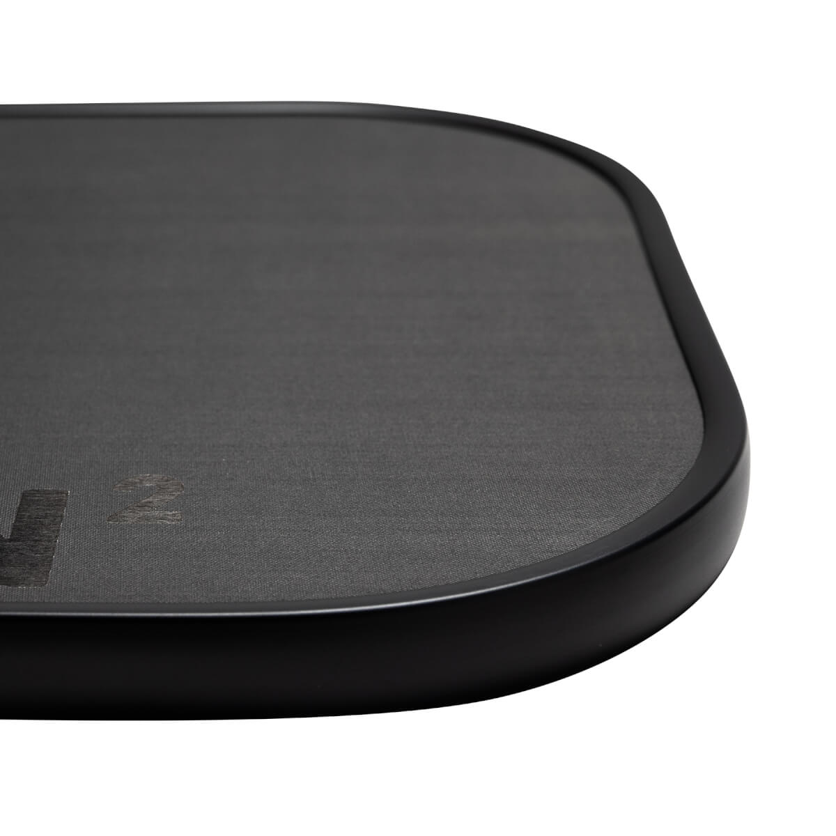 Close-up of a black pickleball paddle with a textured surface and visible CRBN 2 branding.