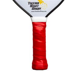 Close-up of a red pickleball paddle grip with a white band and Third Shot Drop logo.