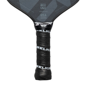 Close-up of a black pickleball paddle grip with Selkirk branding and a textured pattern.