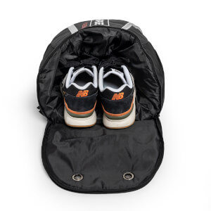 Top-down view of a black pickleball backpack with a pair of black and orange sneakers inside.