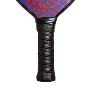 Close-up of a black pickleball paddle grip with red stitching and perforated texture.