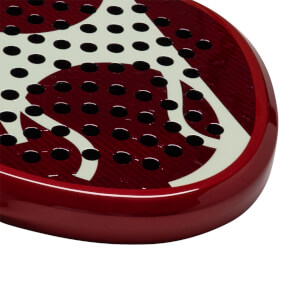 Corner view of a red padel racket with white abstract design and black circular holes.