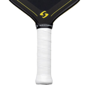 Close-up of a pickleball paddle handle showing white grip tape with embossed "GEARBOX" text and the black neck with yellow accents and a yellow "S" logo.