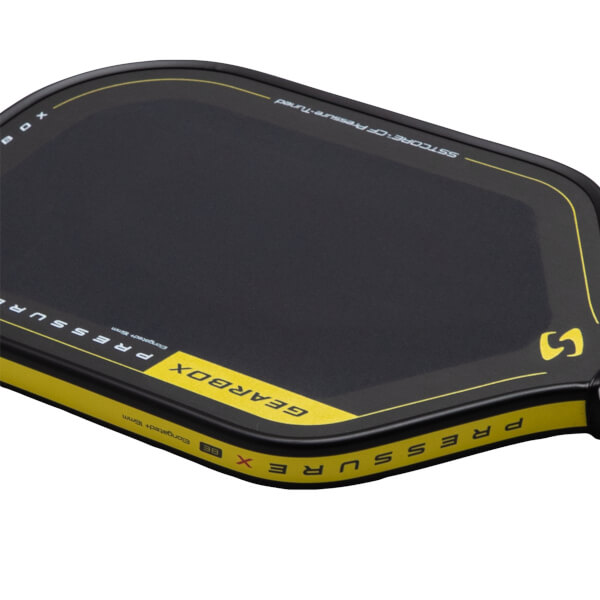 Corner view of a black pickleball paddle with yellow accents, showing "GEARBOX" and "PRESSURE" text.