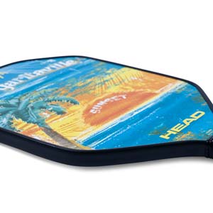 Side view of a colorful pickleball paddle with a sunset beach graphic and HEAD logo.