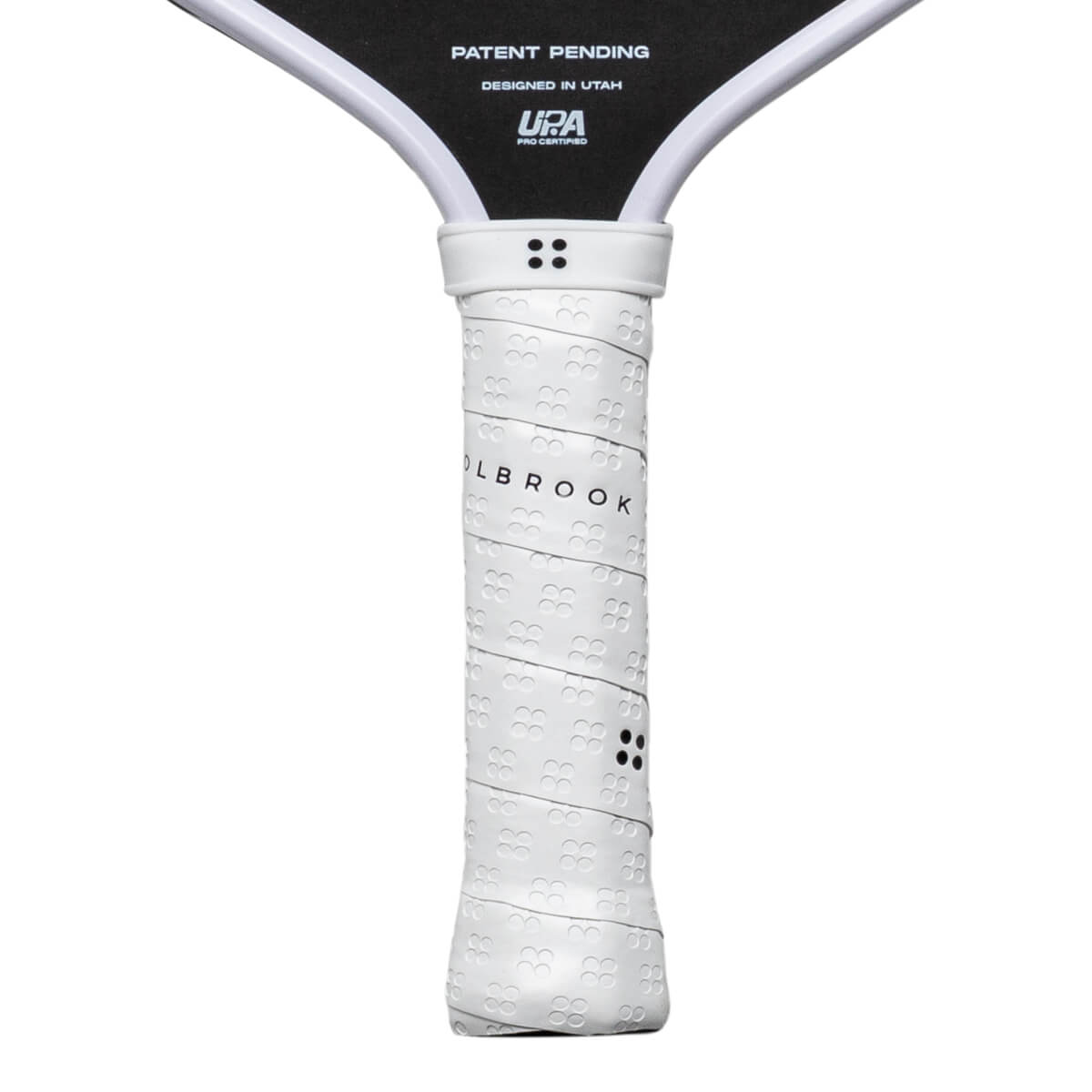 Close-up of a white pickleball paddle grip with "OLBROOK" text and a textured pattern.