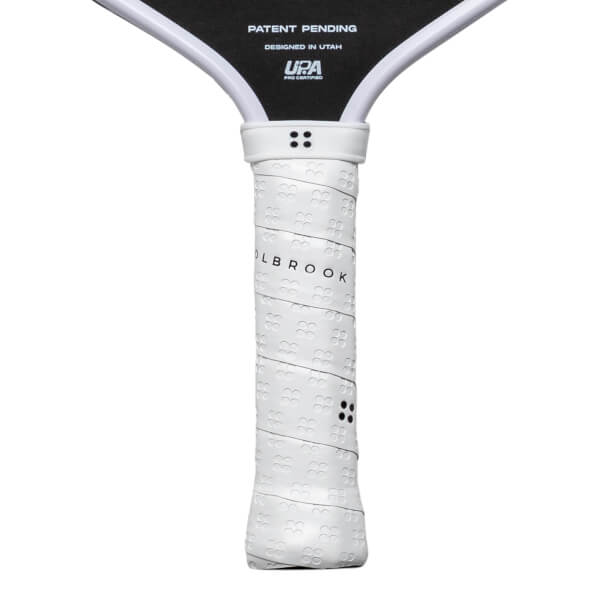 Close-up of a white pickleball paddle grip with "OLBROOK" text and a textured pattern.