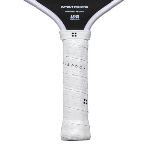 Close-up of a white pickleball paddle grip with "OLBROOK" text and a textured pattern.
