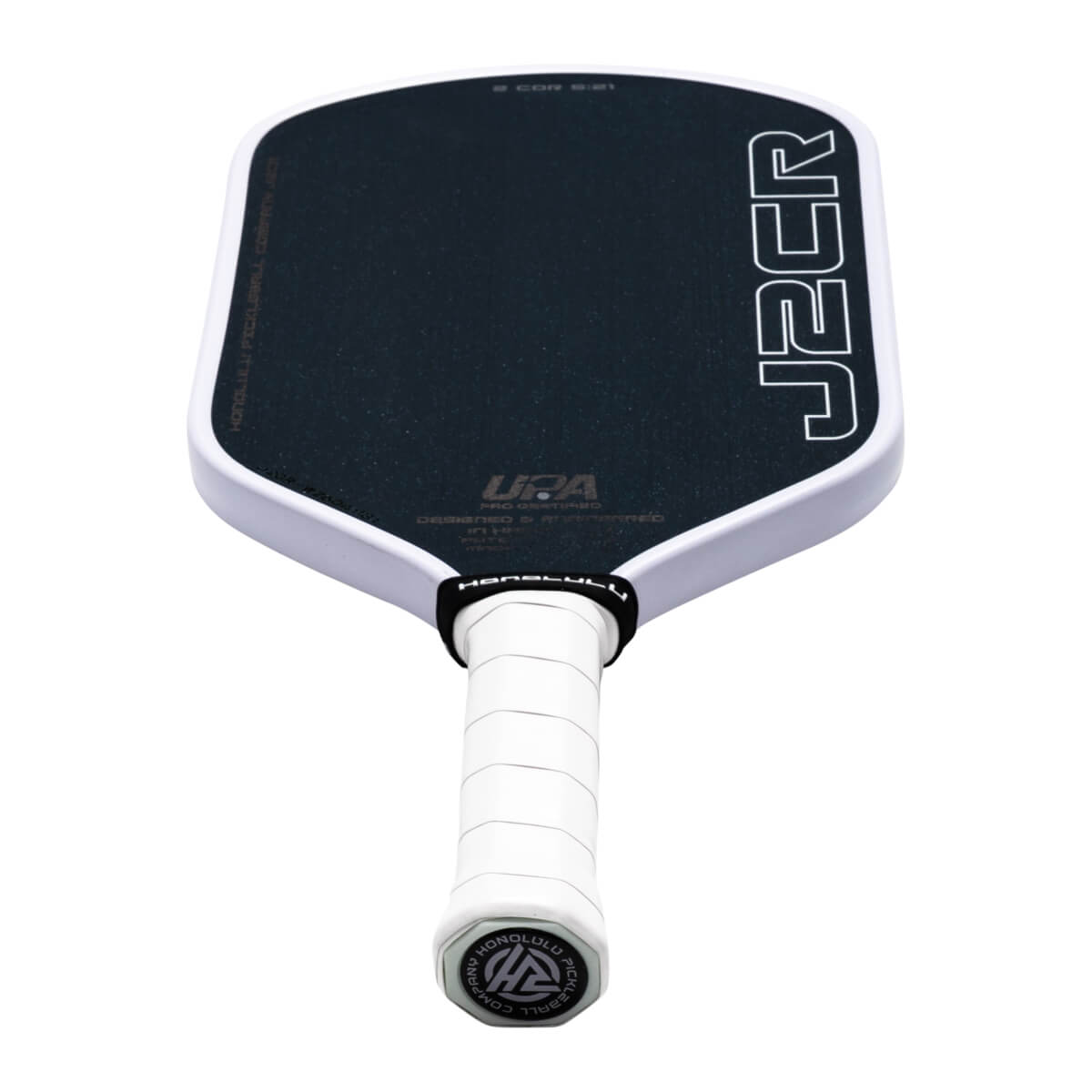 Perspective view from the handle of a black pickleball paddle with white edges, vertical "J2CR" text, and a white grip featuring the Honolulu Pickleball Company logo on the end cap.